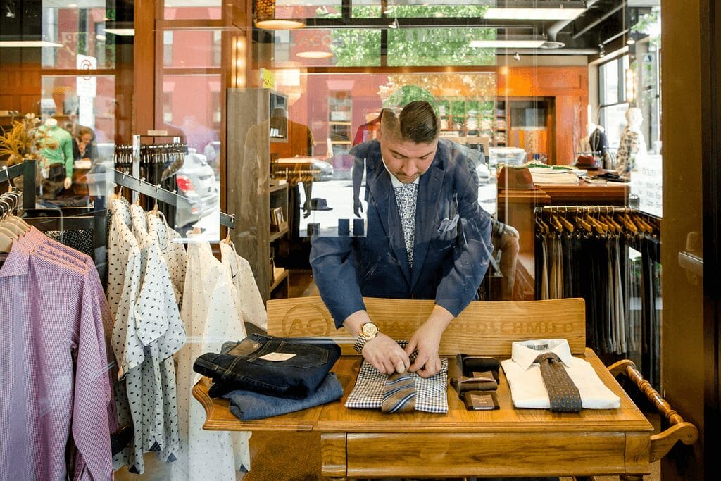 a man in a suit folding a tie.