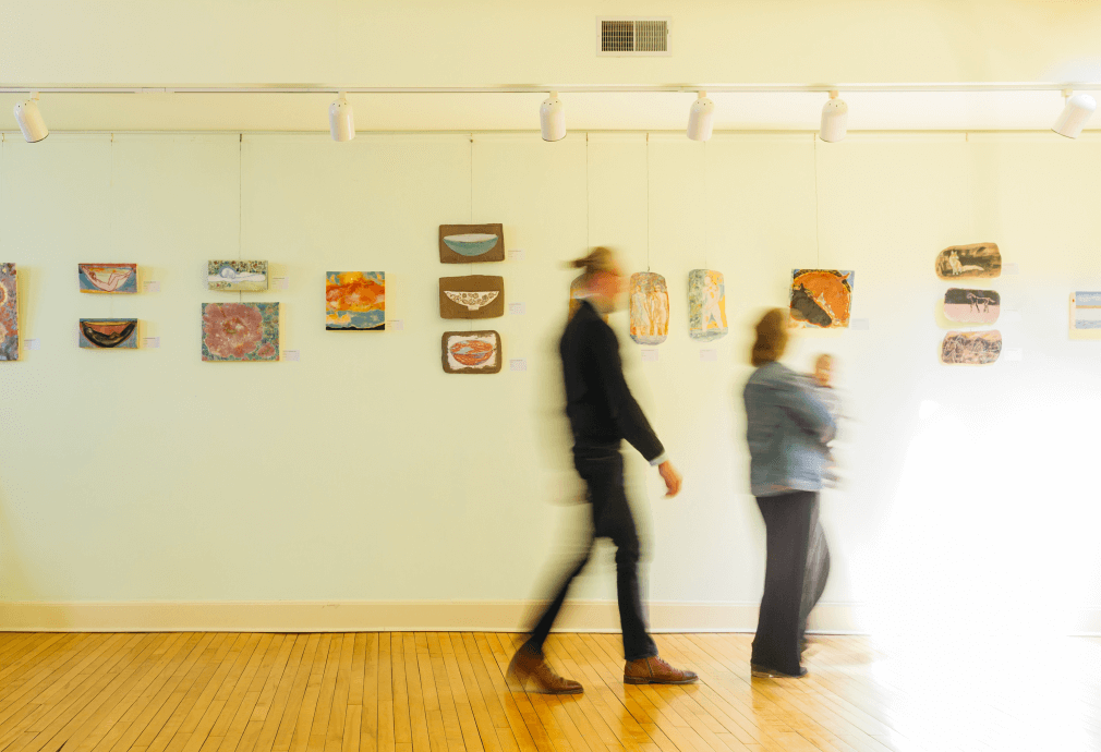 a group of people walking in a room with art on the wall.