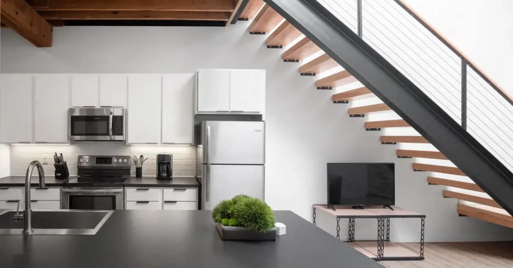 Interior of Bostad apartment featuring a kitchen with a staircase and a black table.