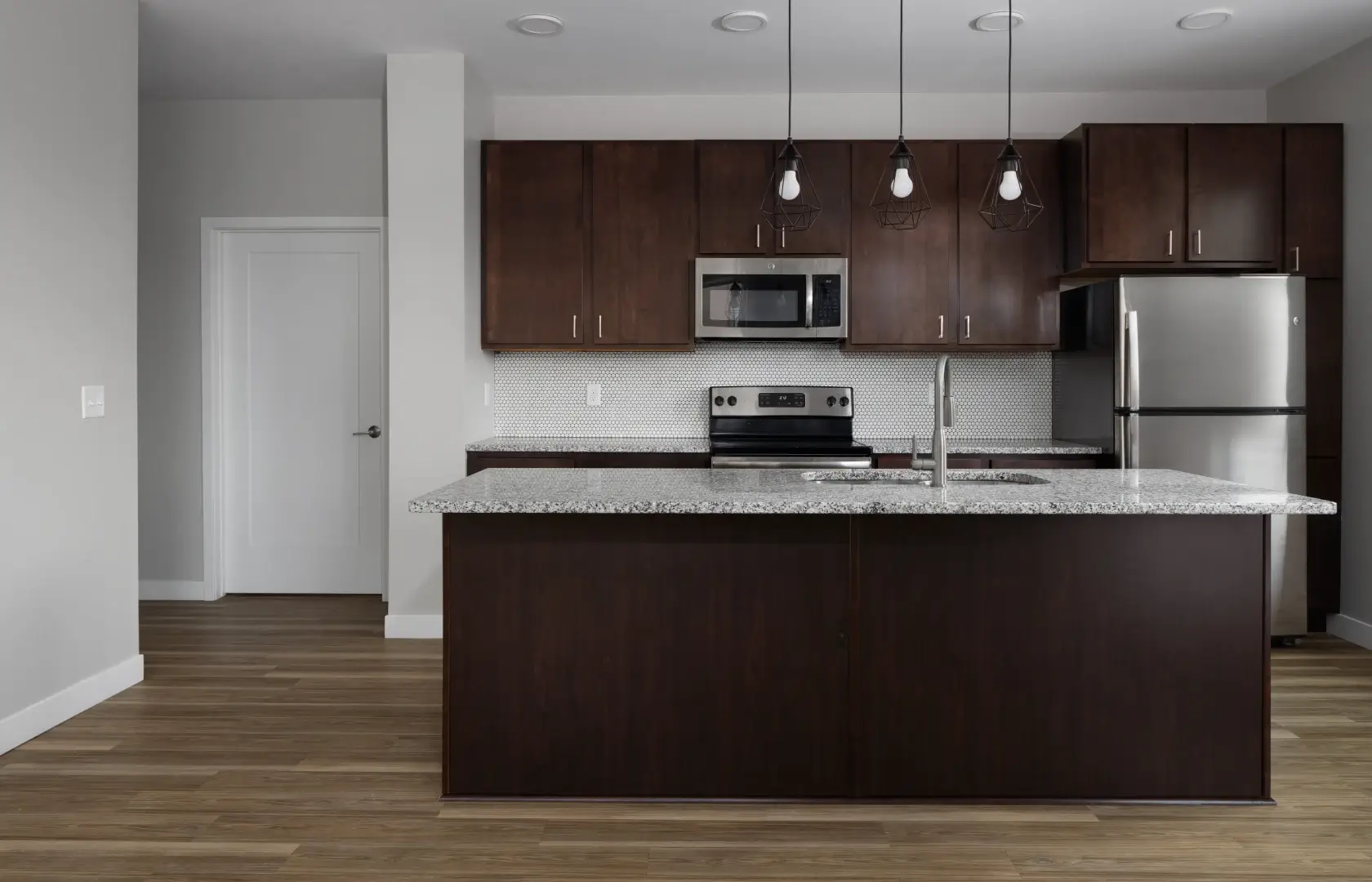 Roco apartment features a kitchen with dark cabinets and a marble countertop.