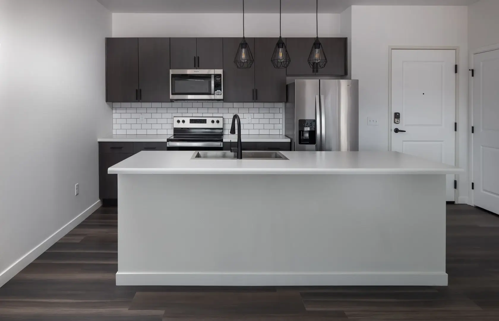 a kitchen with a white island and dark cabinets
