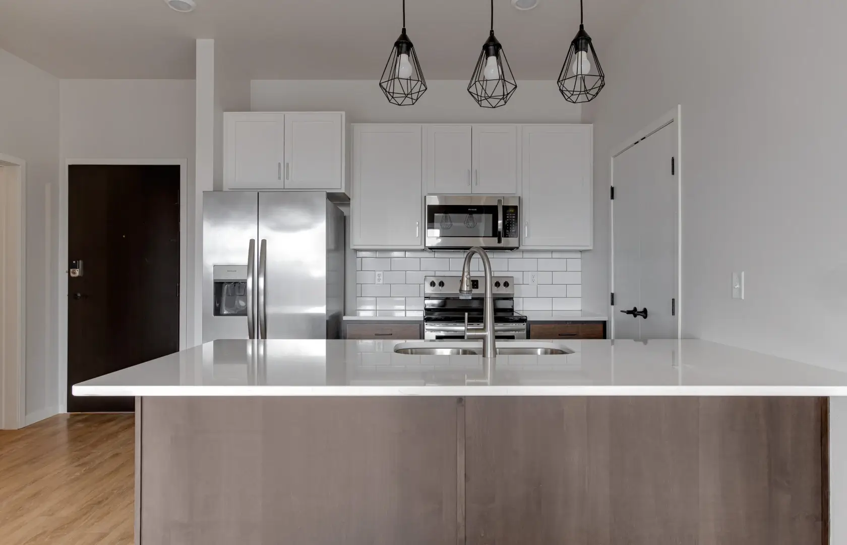 Mercantile apartment with a kitchen featuring a white countertop and a stainless steel refrigerator.